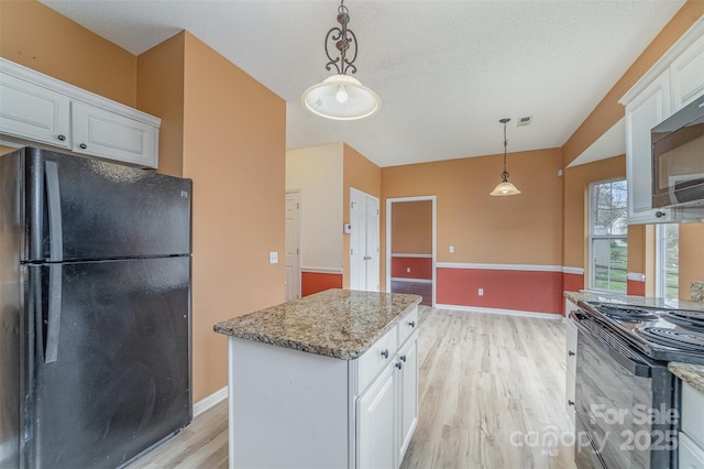 kitchen featuring light stone counters, black appliances, white cabinets, light wood-style floors, and decorative light fixtures