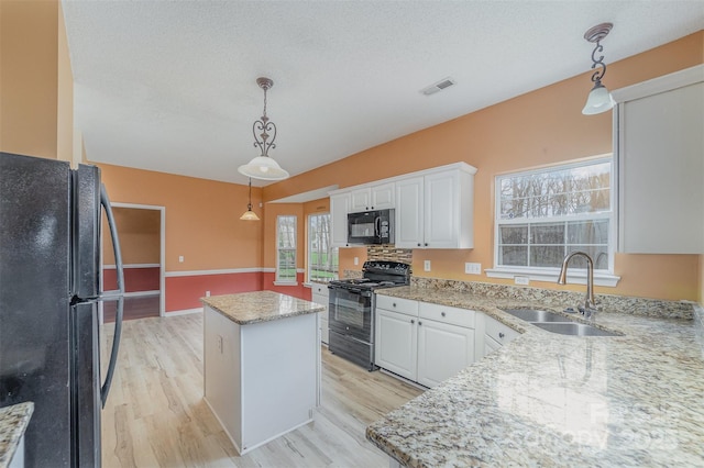 kitchen featuring black appliances, light wood-style flooring, a sink, a center island, and white cabinetry