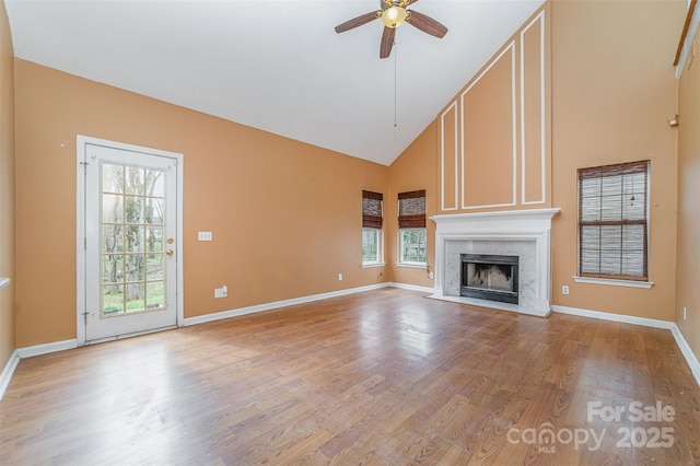 unfurnished living room with high vaulted ceiling, a ceiling fan, light wood-style floors, a fireplace, and baseboards