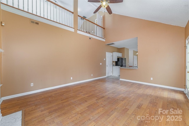 unfurnished living room featuring baseboards, visible vents, light wood-type flooring, and ceiling fan