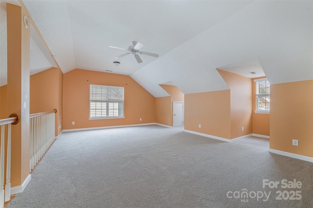 additional living space featuring vaulted ceiling, carpet flooring, a ceiling fan, and baseboards