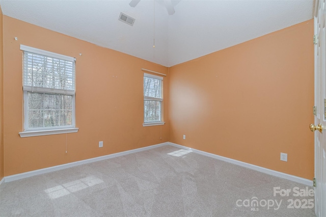 carpeted empty room with visible vents, baseboards, ceiling fan, and vaulted ceiling