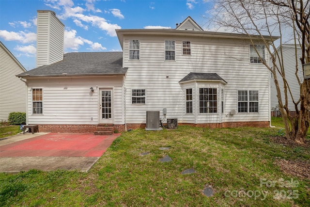 back of house featuring cooling unit, a shingled roof, entry steps, a patio area, and a lawn