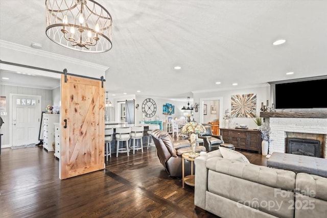 living room with ornamental molding, a textured ceiling, a barn door, a fireplace, and a chandelier