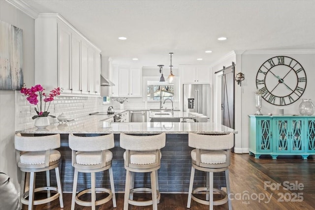 kitchen featuring sink, a barn door, light stone counters, stainless steel fridge, and white cabinets