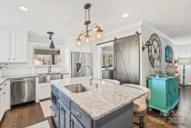 kitchen featuring a barn door, white cabinets, a kitchen island, and appliances with stainless steel finishes