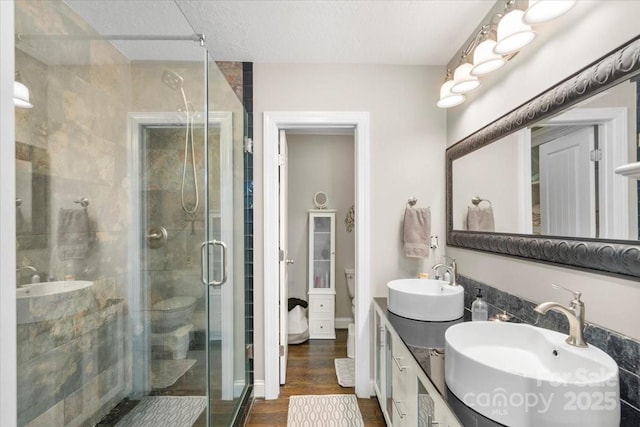 bathroom with hardwood / wood-style flooring, vanity, a textured ceiling, and walk in shower