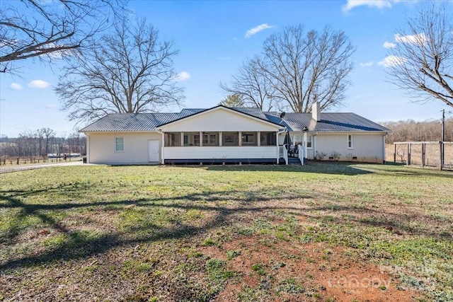 back of property with a sunroom and a lawn