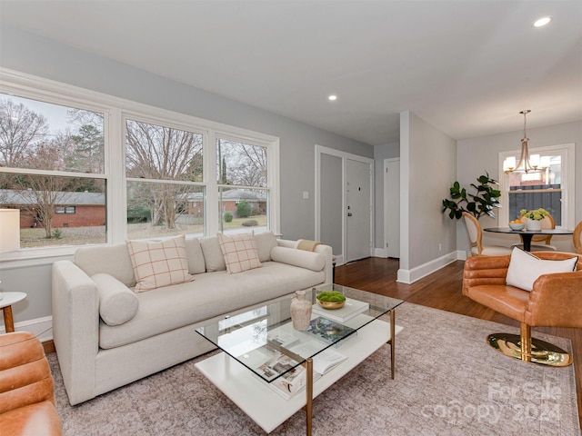 living room with a healthy amount of sunlight, wood-type flooring, and an inviting chandelier