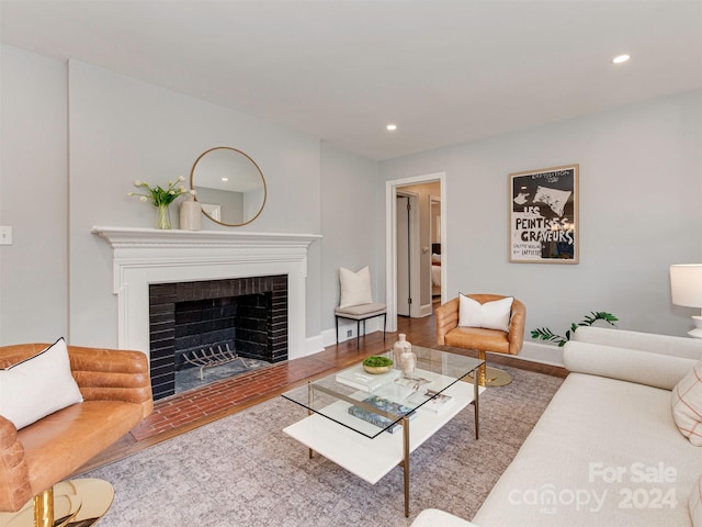 living room with hardwood / wood-style flooring and a brick fireplace