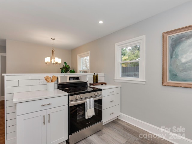 kitchen featuring white cabinetry, stainless steel range oven, a notable chandelier, pendant lighting, and light wood-type flooring