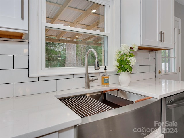 interior details with backsplash, white cabinetry, dishwasher, and sink