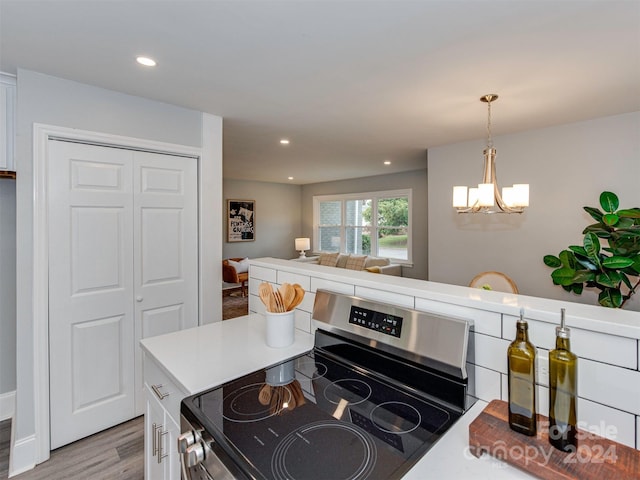 kitchen with stainless steel range with electric stovetop, an inviting chandelier, white cabinets, decorative light fixtures, and light hardwood / wood-style floors