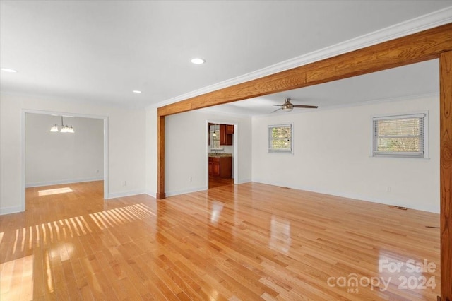 unfurnished room with light hardwood / wood-style flooring, ceiling fan with notable chandelier, and ornamental molding