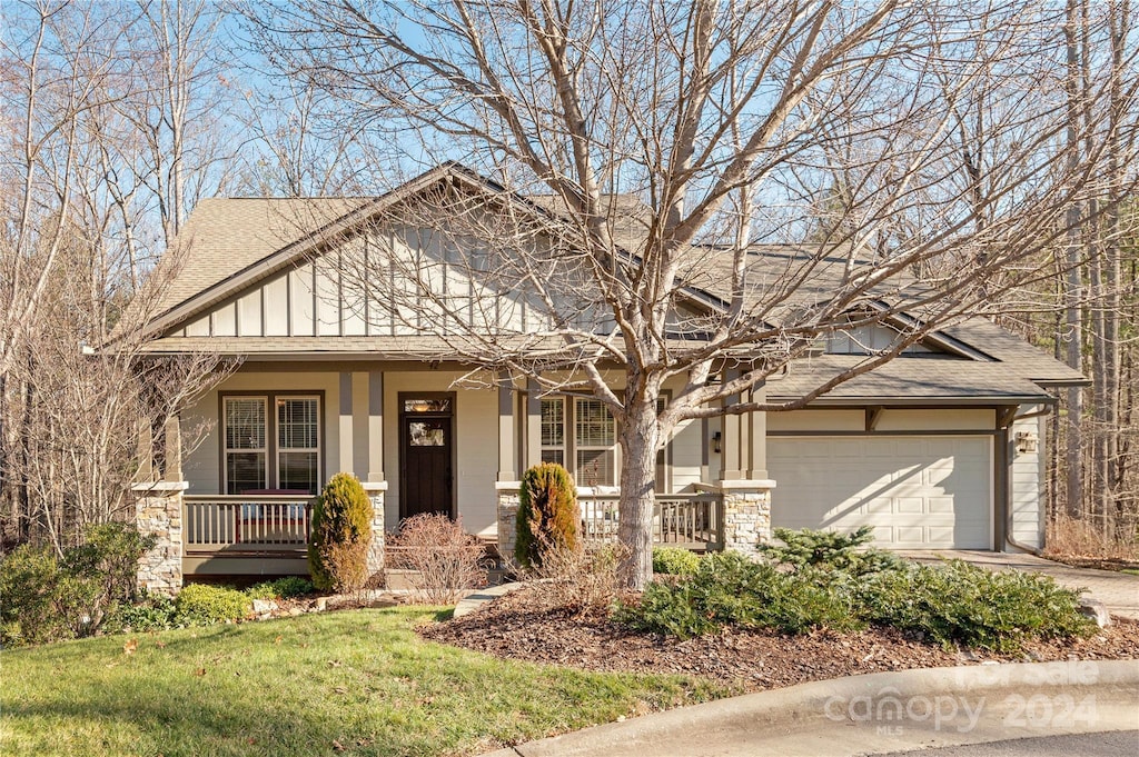 view of front of property featuring covered porch, a garage, and a front lawn