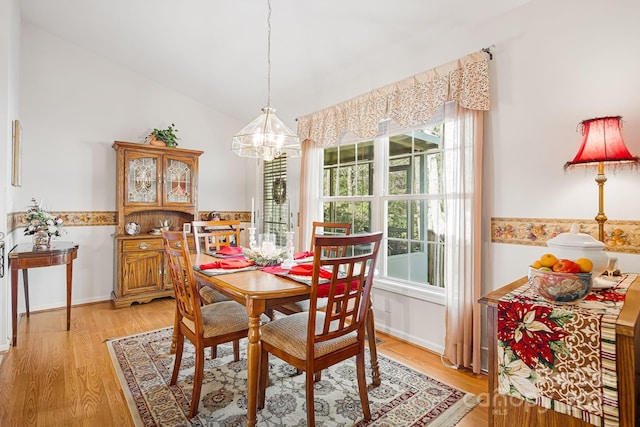 dining area featuring an inviting chandelier, vaulted ceiling, and light hardwood / wood-style flooring