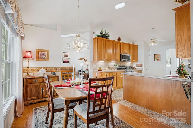 dining area with ceiling fan with notable chandelier and light hardwood / wood-style floors