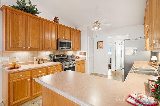 kitchen with backsplash, sink, ceiling fan, kitchen peninsula, and stainless steel appliances