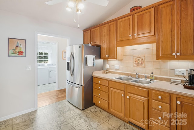 kitchen with vaulted ceiling, ceiling fan, sink, stainless steel fridge with ice dispenser, and washing machine and dryer