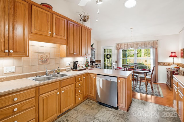 kitchen featuring dishwasher, sink, kitchen peninsula, pendant lighting, and lofted ceiling