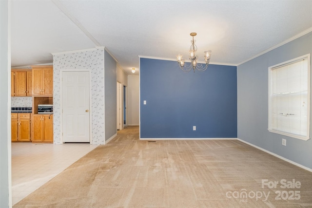 carpeted spare room with ornamental molding and an inviting chandelier