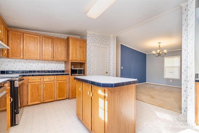 kitchen featuring a center island, hanging light fixtures, crown molding, stove, and a chandelier