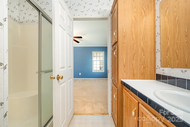 bathroom featuring ceiling fan, vanity, and an enclosed shower