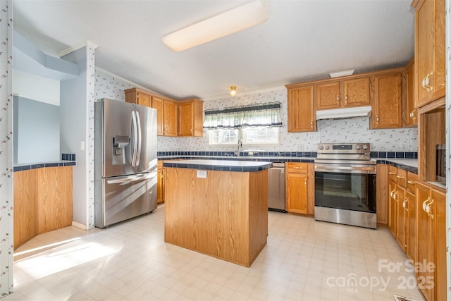 kitchen with a breakfast bar, appliances with stainless steel finishes, a center island, and sink