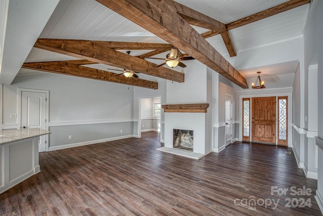 unfurnished living room featuring ceiling fan with notable chandelier, a brick fireplace, vaulted ceiling with beams, dark hardwood / wood-style floors, and a healthy amount of sunlight