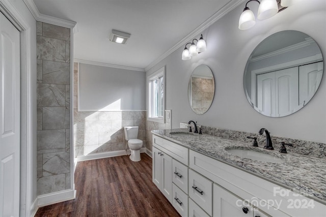 bathroom featuring wood-type flooring, toilet, vanity, tile walls, and ornamental molding