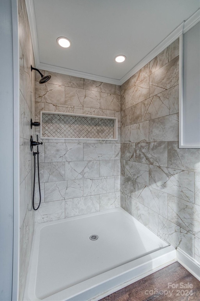 bathroom with tiled shower, hardwood / wood-style floors, and ornamental molding