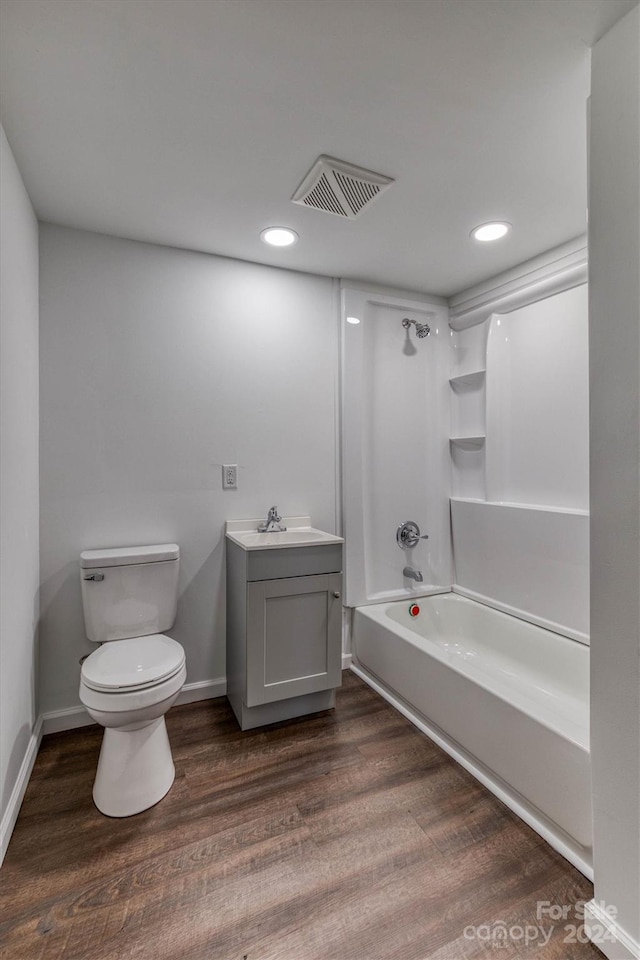 full bathroom with hardwood / wood-style flooring, vanity,  shower combination, and toilet