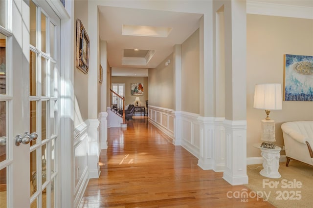 corridor featuring decorative columns, light hardwood / wood-style flooring, and crown molding