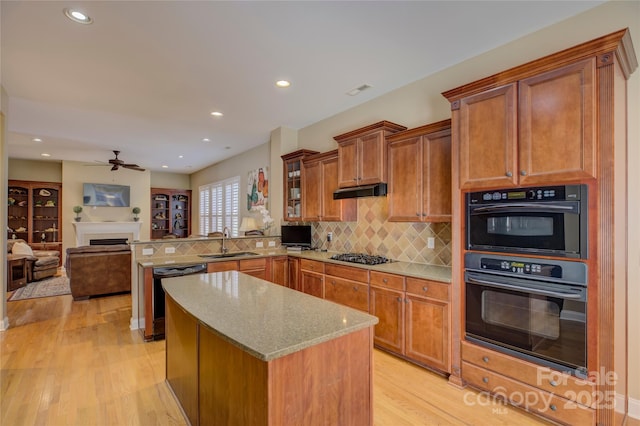 kitchen featuring sink, tasteful backsplash, light hardwood / wood-style flooring, kitchen peninsula, and black appliances