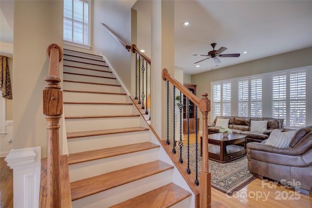 staircase featuring ceiling fan and hardwood / wood-style floors