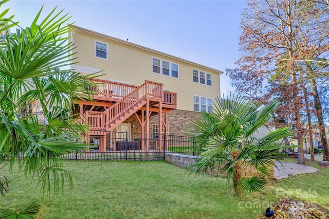 rear view of property featuring a wooden deck and a lawn