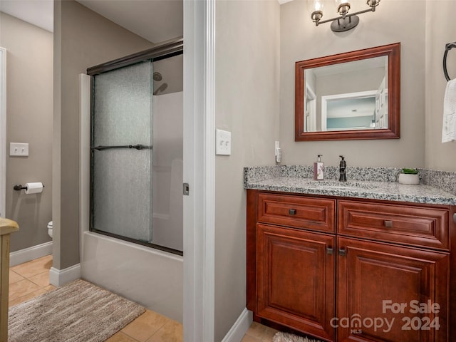 full bathroom with toilet, vanity, tile patterned floors, and bath / shower combo with glass door