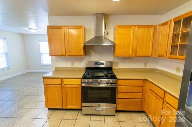 kitchen with gas range, a textured ceiling, wall chimney exhaust hood, and light tile patterned flooring