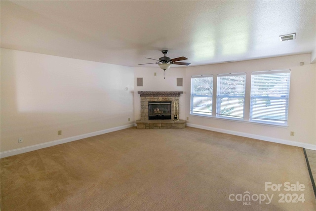 unfurnished living room featuring a fireplace, a textured ceiling, carpet flooring, and ceiling fan