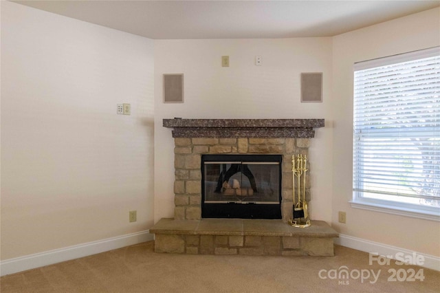 interior details featuring a stone fireplace and carpet