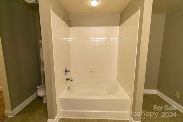 bathroom featuring tile patterned flooring, toilet, and bathing tub / shower combination