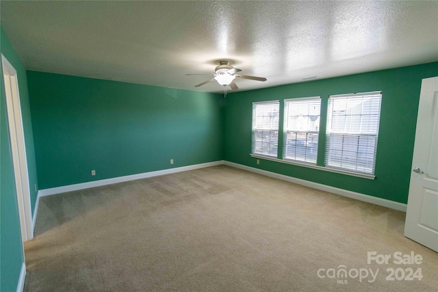 spare room with ceiling fan, light colored carpet, and a textured ceiling