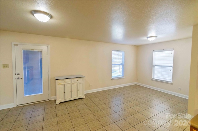 spare room with light tile patterned floors and a textured ceiling