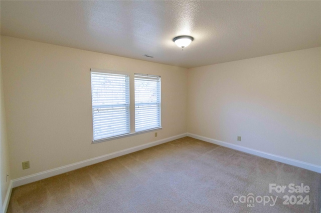 carpeted empty room featuring a textured ceiling