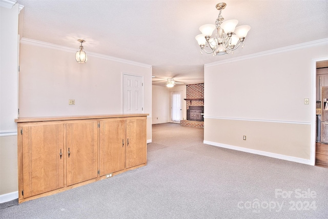 empty room featuring a brick fireplace, a textured ceiling, light carpet, ceiling fan with notable chandelier, and ornamental molding