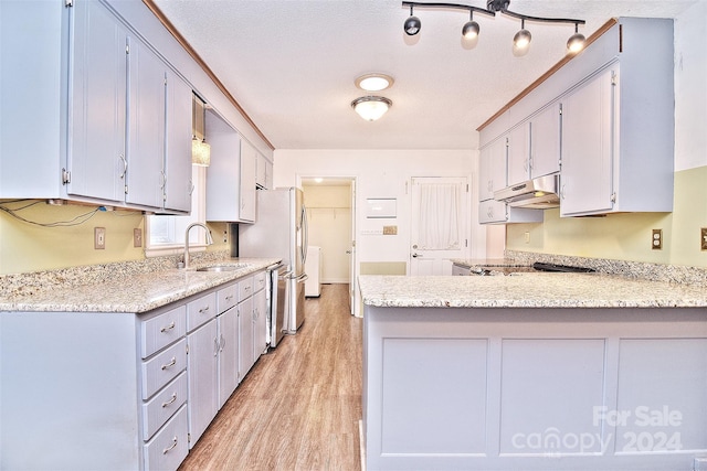 kitchen featuring pendant lighting, sink, light hardwood / wood-style flooring, appliances with stainless steel finishes, and kitchen peninsula