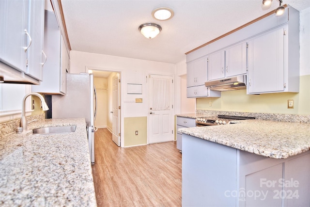 kitchen with light stone countertops, a textured ceiling, light hardwood / wood-style floors, and sink