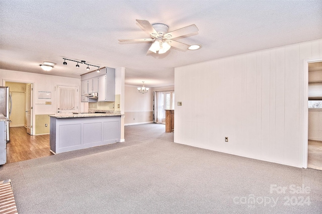 kitchen with stainless steel refrigerator, white cabinetry, ceiling fan with notable chandelier, and a textured ceiling