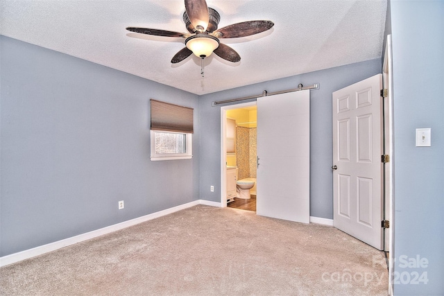 unfurnished bedroom with light carpet, a textured ceiling, connected bathroom, and ceiling fan