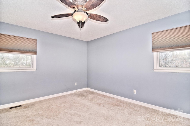 spare room with ceiling fan, light colored carpet, and a textured ceiling